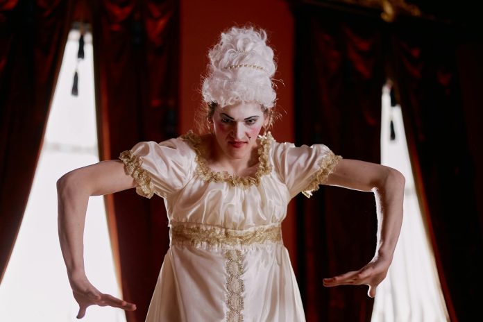 A woman in period clothing looks thoughtfully to the side.